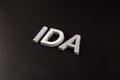 the word ida laid with silver metal letters over dry black matte surface