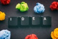 The word Idea on a black background with some colorful crumpled paper balls around it Royalty Free Stock Photo