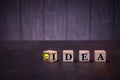 The word idea and sigh light bulb on wooden cubes, on a dark background, light wooden cubes signs Royalty Free Stock Photo