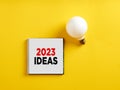 The word 2023 ideas on notepad with a light bulb. New business year creative, innovative, successful ideas and goals concept