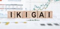 Word IKIGAI made with wood building blocks on background from financial graphs and charts