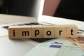 Word Import made of wooden cubes and banknotes on laptop, closeup