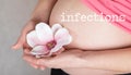 Word INFECTIONS. Young pregnant woman keeps artificial orchid flower close to her belly Royalty Free Stock Photo