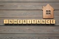 Word Inheritance made with cubes and house model on wooden background, flat lay Royalty Free Stock Photo