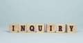 The word INQUIRY made from wooden cubes on blue background