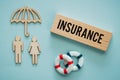 the word Insurance on a wooden block, Wooden shapes of people under the insurers protective umbrella, lifebuoys, Property and