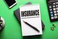 The word INSURANCE is written in a white notebook on a green table near a calculator and a phone. Insurance concept Royalty Free Stock Photo