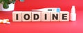 The word IODINE is made of wooden cubes on a red background. Medical concept