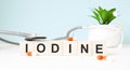 The word IODINE is written on wooden cubes near a stethoscope on a wooden background. Medical concept