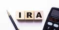 The word IRA Individual Retirement Account is written on wooden cubes between a pen and a calculator on a light background Royalty Free Stock Photo
