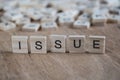 The word issue written with cube letters on wood background