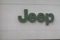 The word Jeep in green letters is seen on the white exterior wall of a car dealership building