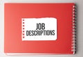 The word Job Descriptions on torn paper on red notepad