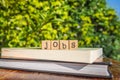 The word JOBS, letters cubes on books with green trees, nature background
