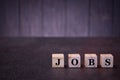 The word jobs on wooden cubes, on a dark background, light wooden cubes signs, symbols signs