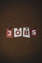 The word Jobs written on colorful note papers on board background. Employment concept. Job search