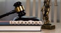 Word JUDGEMENT composed of wooden dices. Wooden gavel and statue of Themis in the background