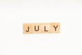 Word JULY made of wooden blocks on white background. Month of year