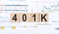 Word 401K made with wood building blocks on background from financial graphs and charts