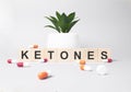 Word KETONES made from wooden letters on grey backgound. Plant on backgound. Medical concept