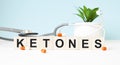 The word KETONES is written on wooden cubes near a stethoscope on a wooden background. Medical concept
