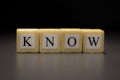 The word KNOW written on wooden cubes isolated on a black background