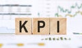 Word KPI - Key performance indicator, made with wood building blocks on background from financial graphs and charts Royalty Free Stock Photo