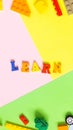 The word `LEARN` is made of colored wooden letters on a multicolored background. Royalty Free Stock Photo