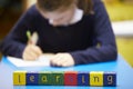 Word Learning Spelt In Wooden Blocks With Pupil Behind