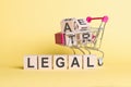 The word LEGAL on wooden cubes, on a yellow background with a shopping trolley Royalty Free Stock Photo