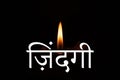 The word life is written in Hindi language on the background of a burning candle in the dark, religion