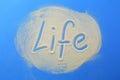 The word life is written in the sand on a blue background. Royalty Free Stock Photo