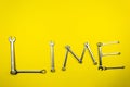 Word `Lime` laid out with wrenches on a yellow background