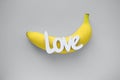 Word LOVE and banana on gray background. Trendy colors of the year 2021 - Gray and Yellow. Royalty Free Stock Photo