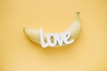 Word LOVE  and banana on yellow background Royalty Free Stock Photo