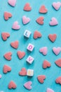 Word Love Constructed from Stacked Letter Cubes. Pink Red Sugar Candy Sprinkles Scattered on Light Blue Background. Valentine Royalty Free Stock Photo