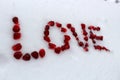 Word Love made of pomegranate seeds on white snow.