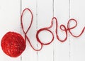 the word love, made of red yarn, is written on a white wooden background Royalty Free Stock Photo