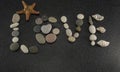 Word LOVE made of sea smooth stones and seashells on black granite with white spots background with starfish Royalty Free Stock Photo