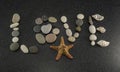 Word LOVE made of sea smooth stones and seashells on black granite with white spots background with starfish Royalty Free Stock Photo