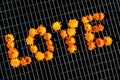 Word Love on a metal mesh fence. Arrangement of pot marigold flowers