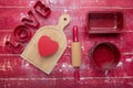 Word LOVE. rolling pins, cookie cutters, and flour on a red wooden background. Heart and cutting board. View from above. Space for Royalty Free Stock Photo
