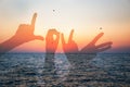 Word love silhouette of two young people making love shape of hands at the beach at sunrise sky summer time, seashore summer beach Royalty Free Stock Photo