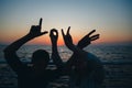 Word love silhouette of two young people making love shape of hands at the beach at sunrise sky summer time, seashore summer beach Royalty Free Stock Photo