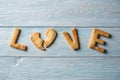 Word love from a sweet cookie in the shape of a broken heart on a blue wooden background. Romantic Valentine`s day gift Royalty Free Stock Photo