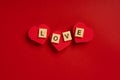 The word `Love` from wooden blocks lies on hearts on a red background. The concept of romantic holidays Royalty Free Stock Photo