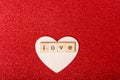 Word love on wooden cubes on wooden heart shape on red background. Love, romance, relationship concept Royalty Free Stock Photo