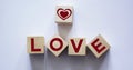 Word Love from wooden letters near red decorative heart on wooden cube and light background Royalty Free Stock Photo