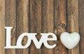 Word love in wooden letters with a white heart beside on a wooden background Royalty Free Stock Photo