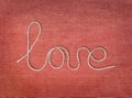 Word love written from rope on red canvas background. Text elements with shadow on pink cotton fabric texture. Close up, top view Royalty Free Stock Photo
